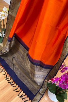 This exquisite adai korvai thread work saree in bright orange is handwoven. The body has navy blue horizontal lines woven while the traditional borders in navy blue shot with black is adorned with paisely and lattice pattern in almond beige colored silk threads. The grand pallu mirrors the borders with additional traditional motifs in almond beige colored silk threads. The blouse piece blue shot with black color with same borders as the saree. Approximate Length 6.5 mtrs (inclusive of blouse length) Height - 46 - 52" Approximate weight - 1.6 lbs Saree comes with fall, picot and tassels done. Blouse piece is cut. Kindly Note : The colors you see on your device may vary due to the color reproduction, brightness and resolution of individual devices. If you'd like more clarity before your purc Blue Shots, Kanjivaram Sarees, Silk Cotton Sarees, Lattice Pattern, Work Sarees, Thread Work, Blouse Length, Silk Thread, Blouse Piece