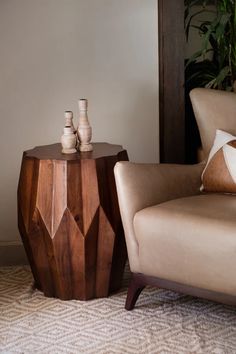 two vases are sitting on a wooden table next to a chair in a living room