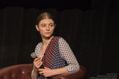 a woman sitting in a chair holding a microphone and looking at the camera with an intense look on her face