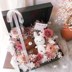 an open box with two stuffed animals and flowers