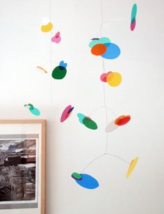 an image of a colorful mobile hanging from the ceiling next to a framed photo and other items