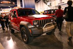 people looking at jeeps on display in a showroom