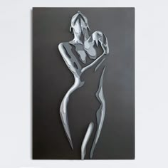 an abstract metal artwork depicting a woman holding a baby in her arms, on a white wall