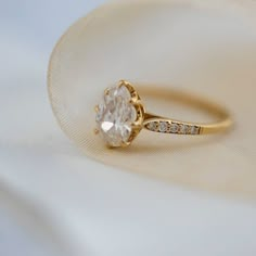 a close up view of a diamond ring on a white cloth with gold trimming