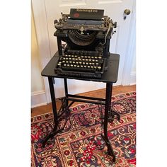 an old fashioned typewriter sitting on top of a table next to a rug and door