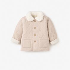 Our soft, cushiony quilted jacket is made from the softest materials and features a stylish, fuzzy vegan sherpa collar for extra warmth during those cold winter months. Pair with one of our coordinating cable knit baby hats or fun pom pom baby hats to complete the look.

Shell: 100% Organic Cotton, Collar: 100% Polyester Vegan Sherpa
Features quilted shell with wooden button closures
Machine wash warm, do not bleach, tumble dry normal, medium iron, do not dry clean Winter White Long Sleeve Quilted Jacket, Cozy Quilted Winter Outerwear, Cozy Cream Cable Knit Outerwear, Long Sleeve Puffer Jacket With Faux Fur Lining, Cotton Cable Knit Outerwear For Cold Weather, Cable Knit Cotton Outerwear For Cold Weather, Cream Quilted Long Sleeve Outerwear, Winter Sherpa Outerwear With Plush Lining, Winter Cotton Quilted Jacket For Cold Weather