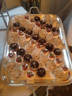 a silver tray filled with cupcakes on top of a table