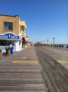 the boardwalk at kohr bros is empty with people walking on it and shops in the background