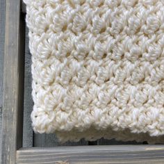 a white crocheted blanket sitting on top of a wooden frame