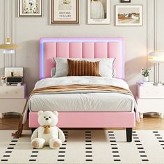 a bedroom with a pink bed, white and gold decor and pictures on the wall