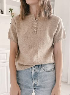 a woman wearing a tan sweater and jeans