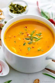 a white bowl filled with carrot soup next to other dishes