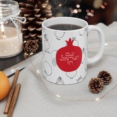 a cup of coffee sitting on top of a table next to pine cones and candles