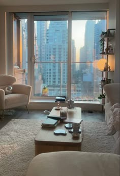 a living room filled with furniture and a large window overlooking a cityscape in the distance