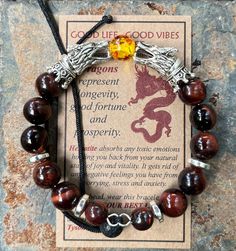 "Introducing the GOOD LIFE/GOOD VIBES bracelet! A bracelet that is beautiful and meaningful.    SYMBOLIC MEANING OF THIS BRACELET: 🔥 Dragons are symbols of prosperity, success and good luck.   The positive energy from this bracelet helps you LIVE YOUR BEST LIFE! This POWERFUL bracelet:   👍 Features SiLVER dragon head beads, 👍 🔥 FIRE DRAGON (red & yellow central bead) or 🧊 ICE DRAGON (clear central bead), 👍 Has 10mm Red Tiger's Eye Beads interspersed with grey Hematite spacer Beads, 👍 Is m Ice Dragon, Handstamped Bracelet, Bracelet Viking, Dragon Bracelet, Viking Bracelet, Beautiful Dragon, Bracelet Box, Red Tigers Eye, Silver Dragon