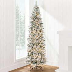 a white christmas tree in a living room with wood flooring and walls painted white