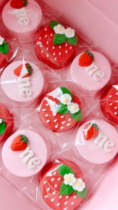 strawberry cupcakes in a pink box with white frosting and decorated strawberries