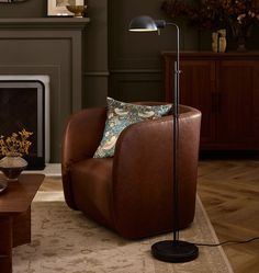 a living room with a brown chair and a lamp on the floor in front of a fireplace