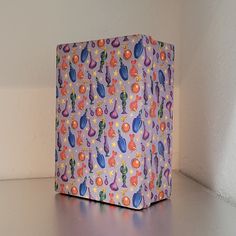 a purple box with colorful designs on it sitting on a table next to a white wall