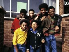 a group of young men standing next to each other in front of a brick building