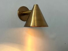 a wall mounted light with a cone shaped shade on it's face and arm