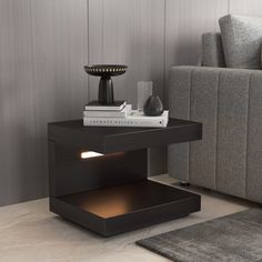 a table with a lamp on it in a living room next to a gray couch