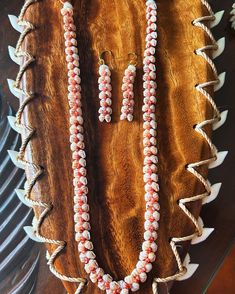 two necklaces and earring on display in a wooden case with other jewelry items