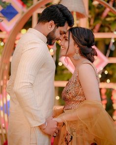 a man and woman standing next to each other in front of a circular arch with lights