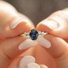 a woman's hands holding a ring with a blue and white stone in it