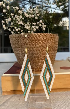 a pair of beaded earrings sitting on top of a table next to a potted plant