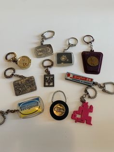 many different types of keychains and badges on a white surface, including one with a bottle opener