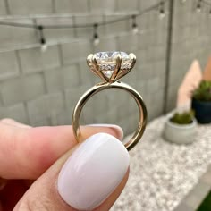 a person holding up a ring with a diamond on the top and bottom part, in front of a brick wall