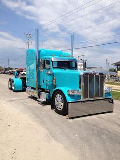 two blue semi trucks are parked on the side of the road