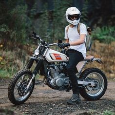 a person sitting on a motorcycle in the woods