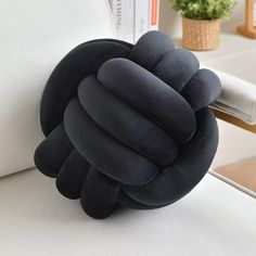 a pillow that is shaped like a knot on the back of a couch with a plant in the background