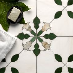 a white and green tiled floor with some leaves on the ground, next to it