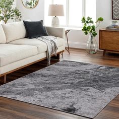 a living room with a couch, chair and rug on the hardwood floor in front of a window