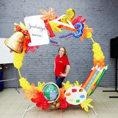 a woman is standing in front of a balloon arch with balloons and other items on it