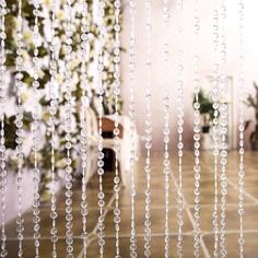 the inside of a room with glass beads hanging from it's ceiling and flowers in the background