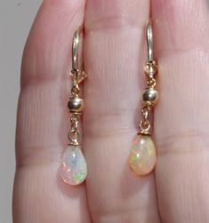 14k gold fiery ethiopian opal elongated lever back earrings ccc fiery ethiopian opal drop lever backs a quality ethiopian opal 7.5 ctw total length of tear drops including bail on avarage: 11- 12mm diameter of round gold balls: 4 mm from top to bottom 35 mm diameter of opals: 7 x12 mm in widest area nice size opal drops Ethereal Earrings, Opal Earrings Dangle, Pearl Earring Jacket, Mermaid Board, Ethereal Jewelry, Pretty Accessories, Tear Drops, Ear Ring, Leverback Earrings