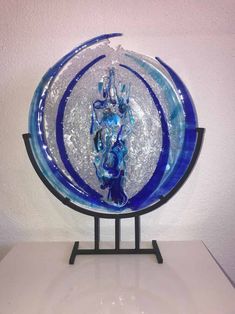 a blue and white glass plate on a stand with water splashing out of it