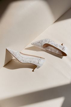 two pairs of wedding shoes sitting on top of a white surface