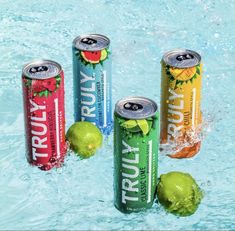 four cans of fruity energy drink in a pool with limes and watermelon