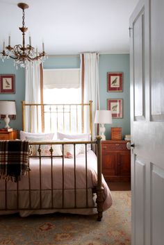 a bed room with a neatly made bed and a chandelier hanging from the ceiling