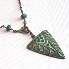 Art Deco Style Necklace - Verdigris Patina Brass Stamping hangs from Ornate Antiqued Brass Connector. The Chain is embellished with small African Turquoise Beads. This necklace also has a tribal look. The pendant is 40mm x 27mm. The design is only on the front side and has a hollow back. Antiqued Brass Chain The patina may vary slightly on the necklace you will receive. This is a stock photo. This particular necklace has been sold. Patina Jewelry, African Turquoise, Gift For Woman, Brass Chain, Style Necklace, Turquoise Beads, Boho Necklace, Art Deco Style, Deco Style