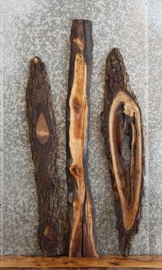 three pieces of wood sitting on top of a wooden shelf in front of a wall