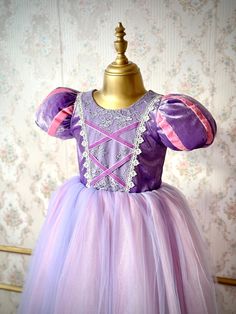 Make your little princess's fairy tale dreams come true with our enchanting Rapunzel costume dress! Perfectly designed for girls, this magical gown features vibrant colors, exquisite lace and ribbon details, and soft, comfortable cotton fabric for all-day play. Ideal for birthdays, dress-up, weddings, photoshoots or any special occasion, let her imagination soar as she steps into the world of enchantment. Let your little one shine and twirl in her very own Rapunzel adventure! ♥ If you want a custom design (in different color, size, fabric, model etc.), please contact us so we can create your dream piece together! * FABRIC: Silk Velvet and long tulle with Cotton lining. * LINING: 100% Organic Soft Cotton (pre-washed and ironed), ensuring utmost comfort for your little one. * DETAILS: The to Rapunzel Dress For Kids, Purple Princess Ball Gown Dress, Fairytale Princess Dress Ball Gown For Pageant, Fairytale Princess Dress For Pageant, Fairytale Princess Dress For Pageants, Fairytale Princess Ball Gown Dress, Fairytale Princess Dress Ball Gown For Dress-up, Princess Tulle Ball Gown For Fancy Dress, Princess Style Tulle Ball Gown For Fancy Dress