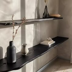 three vases are sitting on a black shelf