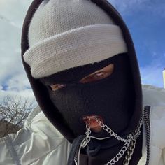 a man wearing a black and white hoodie with chains on his face