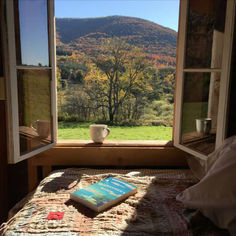 a bed with a book on it in front of a window overlooking a mountain range